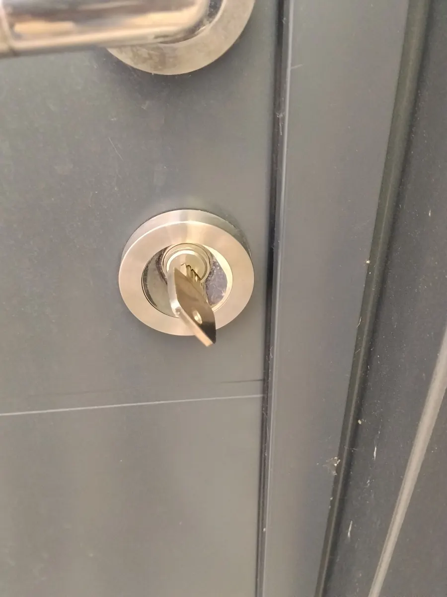 Cylindre de serrure et sa clé sur une porte d'entrée grise